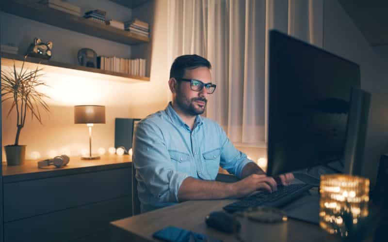 Modern young man working remotely from home at night.