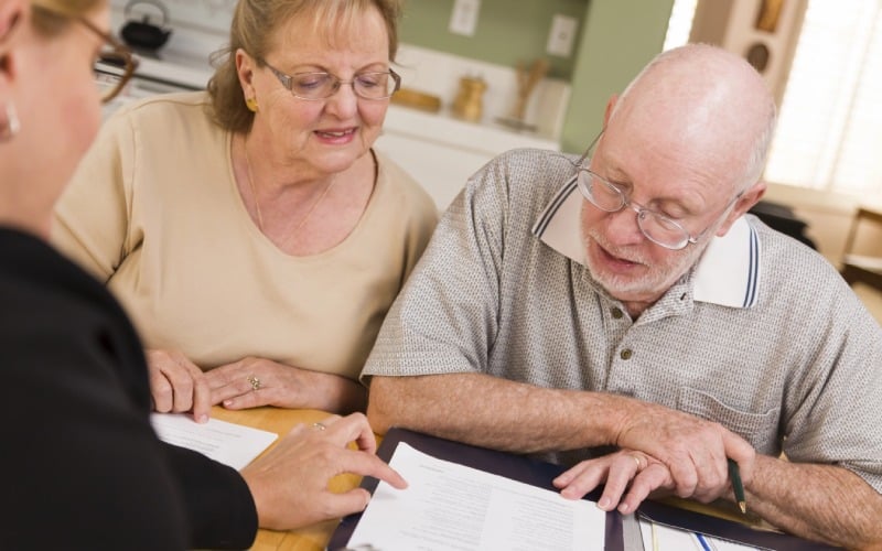 senior adult couple going over papers in their home with agent