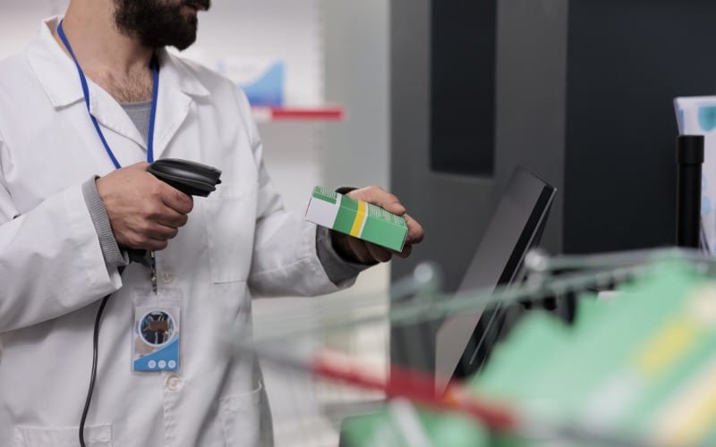 man pharmacist holding store-scanner-that-reads-barcodes all drugs packages